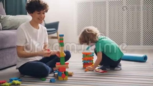 年轻女子正在和孩子玩积木，男孩正在玩视频