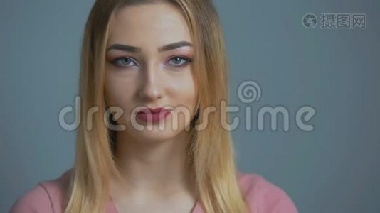 美丽的女孩在彩色的画室背景上微笑，面对一个年轻快乐的女人调情化妆，概念人物和埃莫蒂视频
