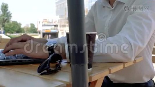 一个穿着白色衬衫，坐在街边咖啡馆里用手提电脑键盘打字的男人的双手紧闭。 商人打字视频