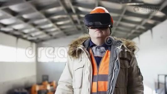 戴着安全帽、穿着工作服的人正站在机库的中间，戴着虚拟现实眼镜的人在驾驶着钻头。视频