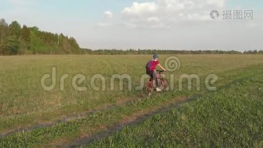 一个年轻的女孩骑自行车在农村的道路上。 四架直升机射击。 从上面看视频