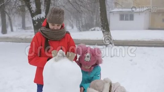 妈妈和两个女儿在冬天装饰鹅卵石一起堆雪人。视频