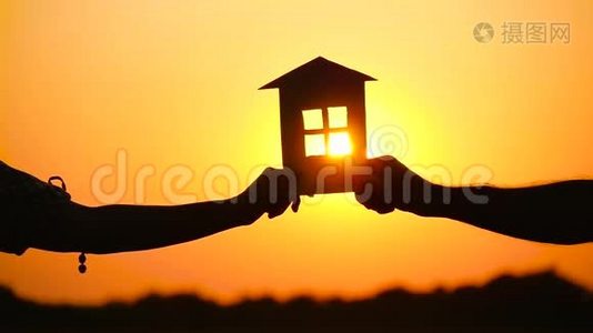 一男一女抱着纸屋对着夕阳.. 屋的剪影.. 建筑主题，真实视频