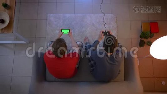 穿着睡衣的朋友在游戏上做出情感反应，并在客厅里使用智能手机。视频