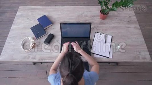 工作日，从顶部可以看到年轻女性在笔记本电脑键盘上输入文字，在办公桌前的剪贴板上写笔记视频