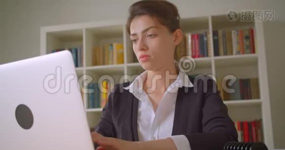 一位年轻漂亮的高加索女商人用笔记本电脑在办公室里用照相机拍摄的特写镜头视频