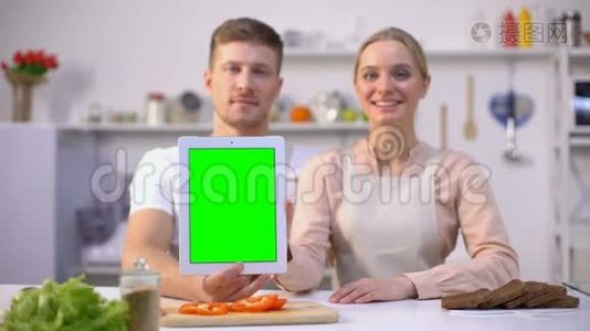 双手拿着绿色屏幕的平板电脑，竖起大拇指，美味的食谱应用程序视频
