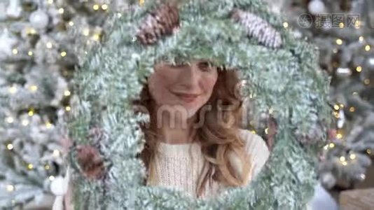 圣诞树背景下一位穿着白色毛衣微笑的女士的新年画像视频