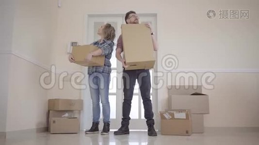 一对年轻夫妇搬进了一个新家。 一对夫妇站在门口，手里拿着箱子。 美丽美丽视频