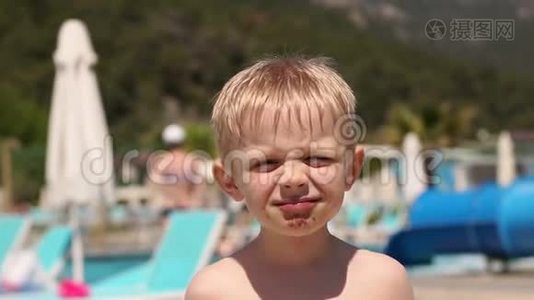 一个小孩子在暑假在游泳池附近吃巧克力冰淇淋。视频