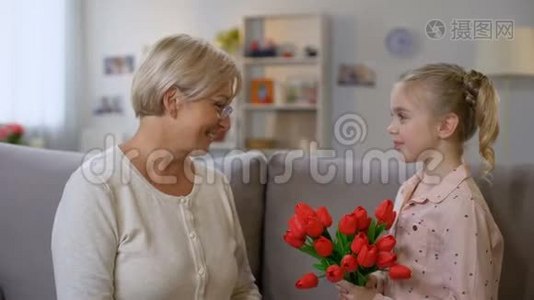 可爱的女孩把红色郁金香送给祖母和拥抱，家人的爱，生日视频