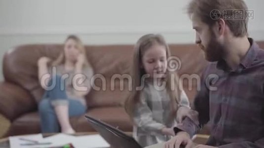 有胡子的人用笔记本电脑近距离工作的肖像。 小女孩摸着男人要钱的手。 刺激性视频