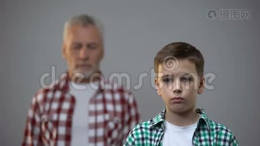 严肃的少年看着镜头，年长的男子背后，与祖先的联系视频