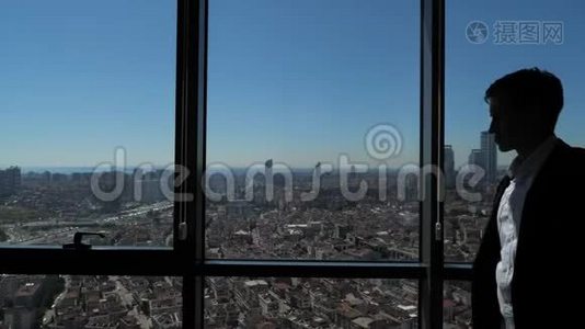 商人的剪影正在他的笔记本电脑附近的全景窗口与城市的视野。视频