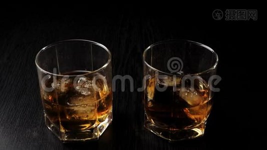 豪华威士忌。 手拿着一杯金色威士忌和真正的冷冰从黑桌上。 不倒翁威士忌。 波旁酒。视频