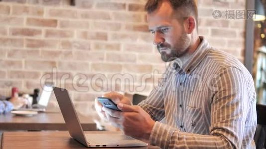 胡子休闲男子使用智能手机和笔记本电脑，坐在户外视频