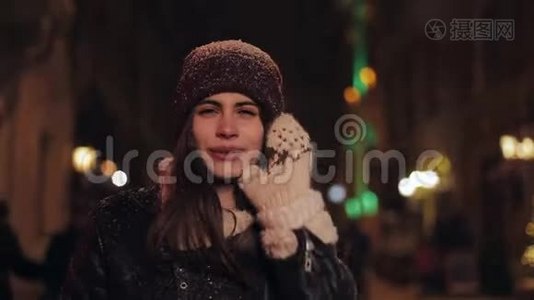 特写一幅年轻快乐、迷人、戴着冬帽、戴着手套、在夜幕下漫步的少女画像视频
