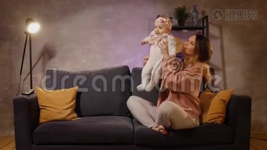 年轻的一家人坐在舒适的房间里的沙发上。 妈妈爸爸和宝宝一起玩.. 家庭幸福视频