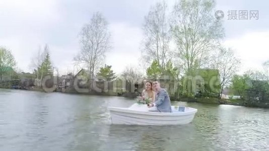 镜头移离坐在白色小船上快乐欢笑的新婚夫妇..视频
