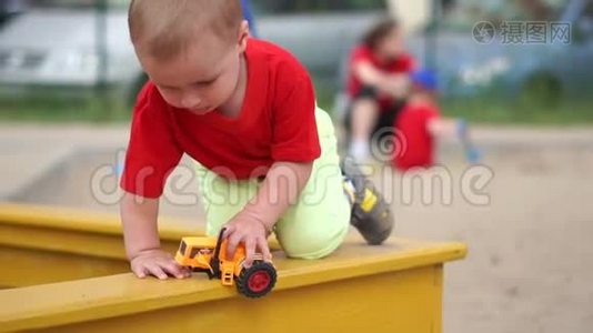 一个金发小男孩在操场上慢悠悠地玩着破拖拉机视频