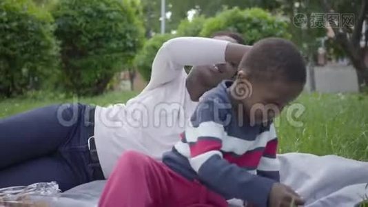 漂亮的非裔美国女人和她的小儿子躺在公园的毯子上。 小妈妈挠痒痒男孩视频