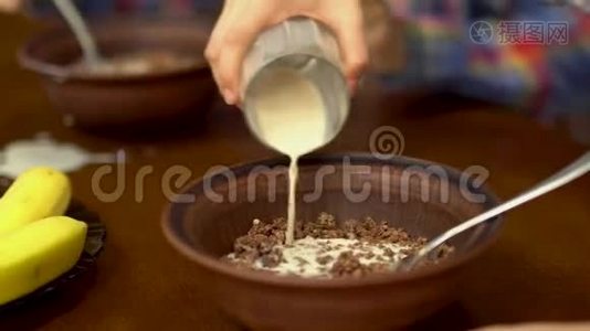 孩子们把杯子里的牛奶倒进碗里的麦片粥。 愉快的友好家庭享受早餐视频