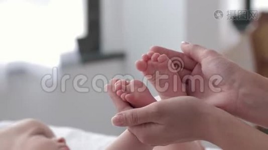 幼小的新生婴儿双脚在妈妈的关怀之手中紧紧地抱着，小女孩正积极地趴在换衣桌上视频