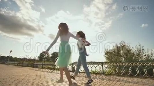 两个友好的女朋友在日落时手牵着手跳着跑。视频