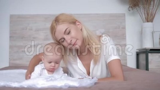 母爱，年轻的父母亲吻新生的女婴，看着躺在床上的镜头视频