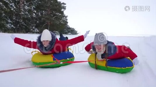 快乐的姐妹们在公园里雪橇和休息，过圣诞节。 冬天穿红色夹克的孩子们骑马视频