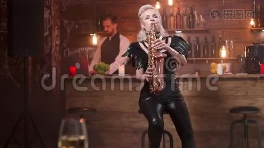 穿着时髦黑衣服的漂亮女人在萨克斯管里玩视频