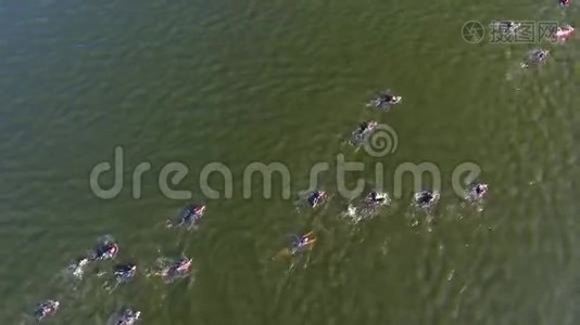 在水上竞赛中，铁人三项选手从上到下穿越深绿色的河流视频