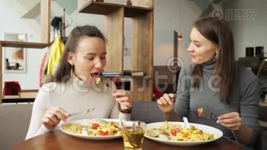 两个女朋友在咖啡馆里一起吃饭，聊天，享受他们的食物。视频
