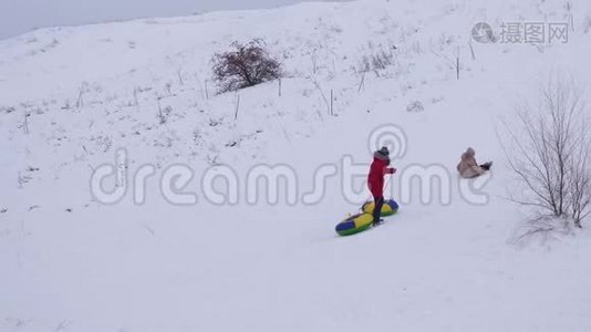 在冬天，少女们坐着雪碟从高高的雪山上骑马。 孩子们在新鲜空气中`冬天的游戏。 快乐的孩子视频