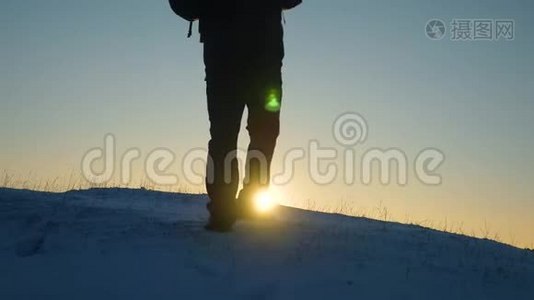 旅行者克服困难走向胜利. 旅行者在阳光的照耀下在一座雪山上站起来。 游客视频