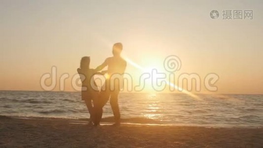 浪漫的年轻夫妇在海滩上，男人在日落时搂着他的女朋友在美丽的海边。 玩得开心视频