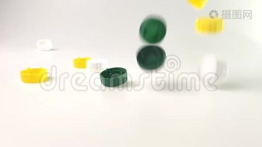 彩色塑料盖子掉在白色背景的桌子上视频