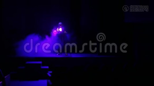 一个照明者用烟雾引导一束光线从舞台上的聚光灯照射到体育馆视频