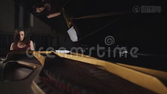 女子在音乐厅弹钢琴的总平面图.. 透过敞开的钢琴看女孩..视频