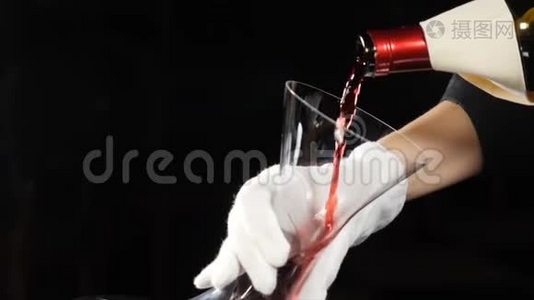 酒庄的概念。 红酒倒在深色背景下的酒壶里。 将红色酒瓶的颈部倒入视频