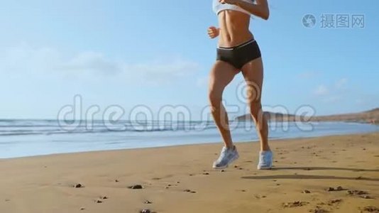 美丽的女人穿着运动短裤和t恤在海滩上奔跑，沙滩上有白色的沙子和蓝色的海水。视频