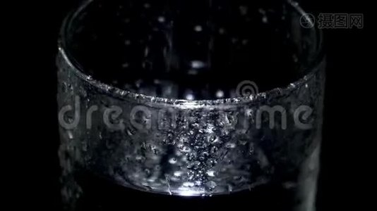 一杯湿玻璃杯里的水在黑暗中旋转，光线在水滴中闪烁视频