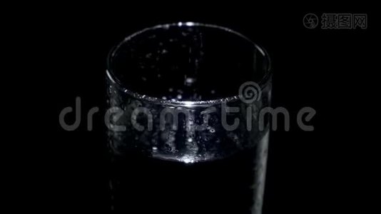 一个装有水和水滴的玻璃在黑暗中旋转视频