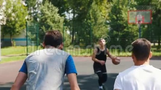 三个运动员在户外球场上打篮球-一个人扔球视频