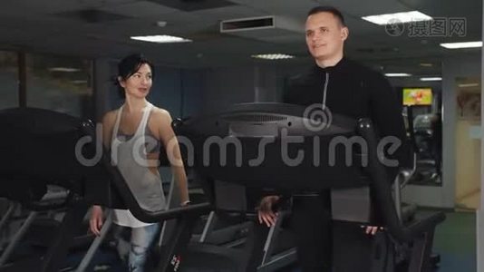 男人和女人一起在运动俱乐部的跑步机上训练。视频