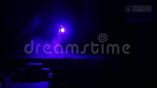 一位年轻的女照明师用烟雾引导一束从舞台的聚光灯到礼堂视频