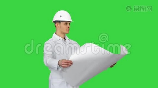 英俊的工程师，建筑师，建筑工人，商人，戴着白色头盔，手里拿着一个项目，看着视频