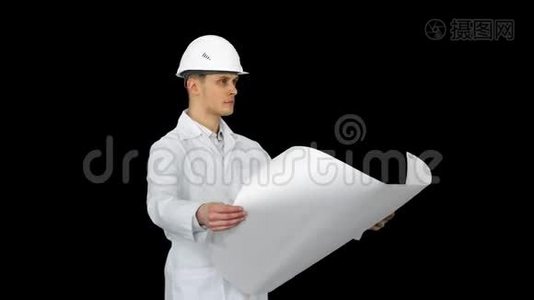 英俊的工程师，建筑师，建筑工人，商人，戴着白色头盔，手里拿着一个项目，看着视频