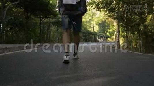 后背低角度观看亚洲女性徒步旅行者与背包走过热带雨林。视频