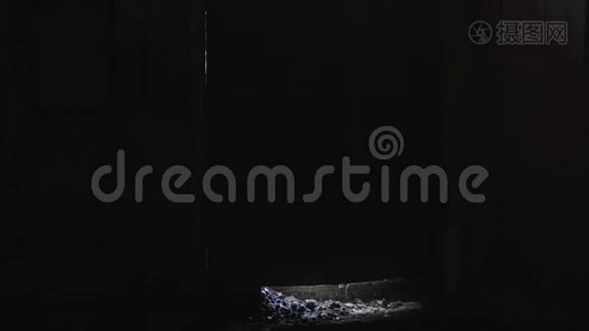 一个穿着黑色雨衣的硬汉踢开了一扇被遗弃的房间的门。视频